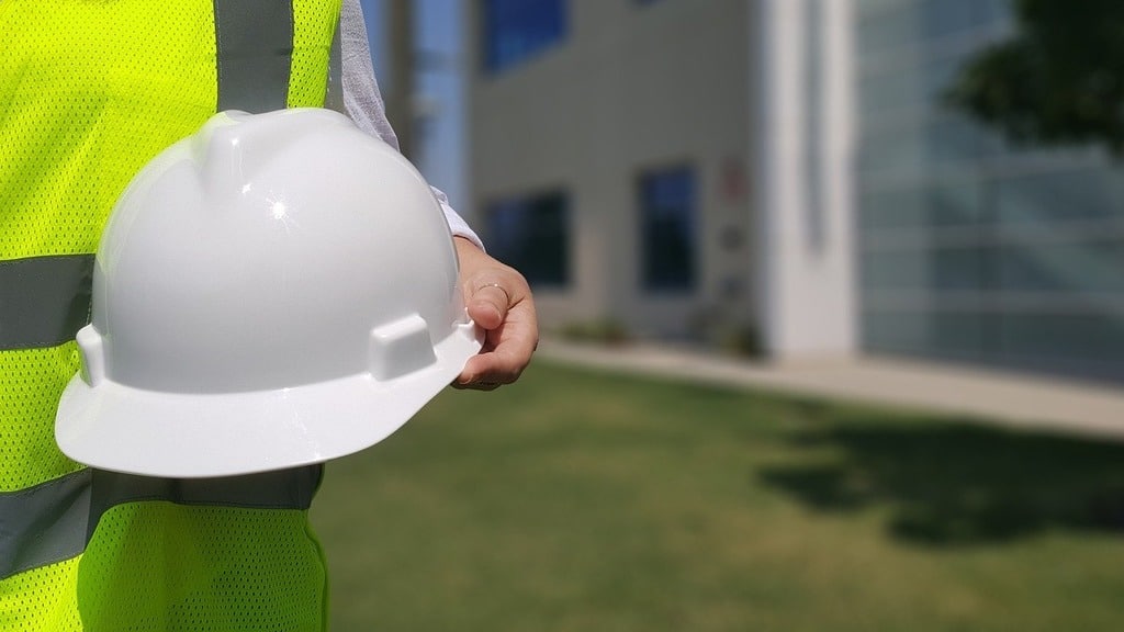 Pessoa usando colete de segurança e segurando capacete, representando segurança do trabalho e SIPAT