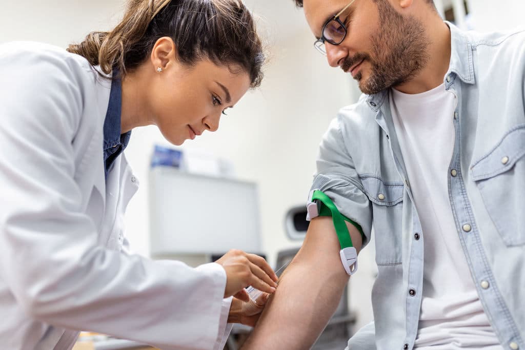 Profissional da saúde colhendo sangue de paciente para exame, representando ele estar regularizando a situação de exame toxicológico vencido
