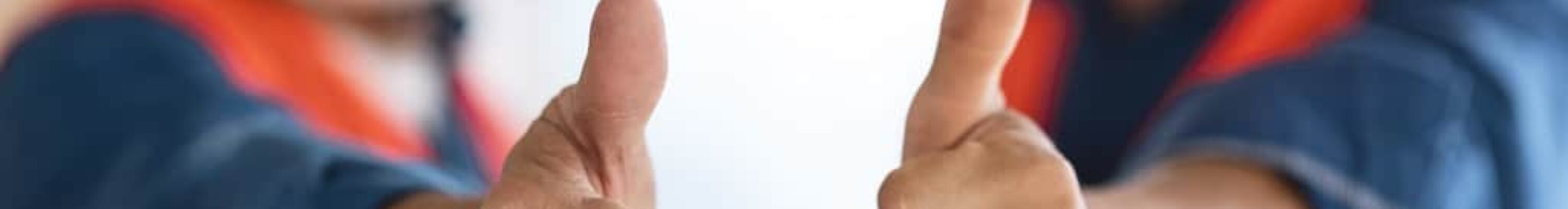 Dois profissionais fazendo sinal de jóia para a câmera e usando EPIs como capacete, máscara e colete; simbolizando por que investir em segurança do trabalho